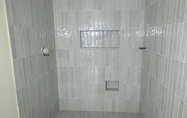 Shower wall finished in vertical stacked ceramic tile with recessed niches