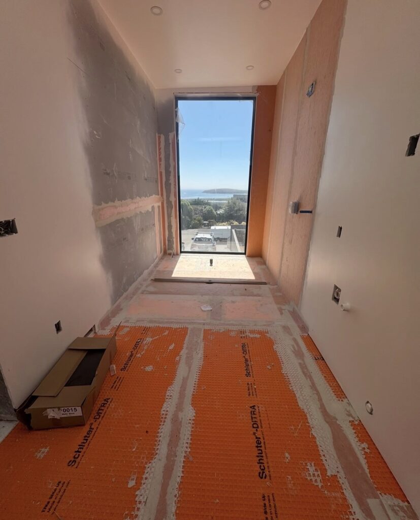 Waterproof membrane installed on a bathroom floor with an ocean view window